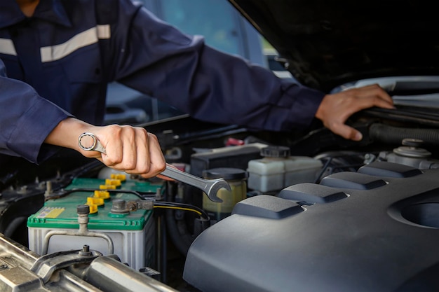 El mecánico trabaja en el motor del auto en el garaje, servicio de reparación de autos.