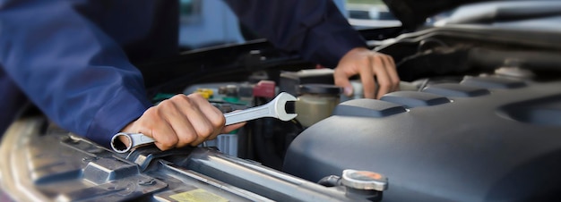 El mecánico trabaja en el motor del automóvil en el servicio de reparación de automóviles del garaje