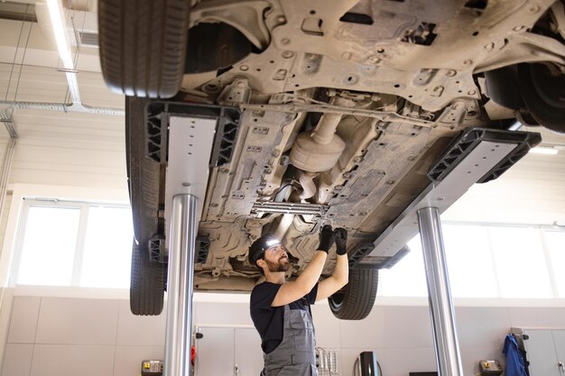 Mecánico trabajando bajo un coche elevado en un taller de reparación de automóviles