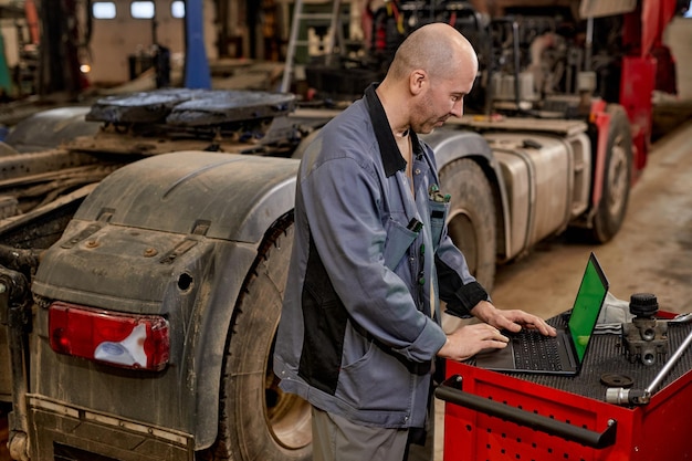 Mecánico trabajando en una computadora portátil en un taller automotriz