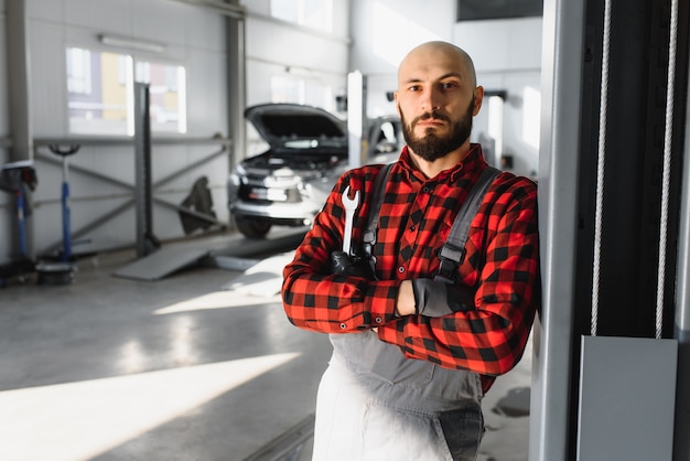 Foto mecánico trabajando y sosteniendo la llave de la orden de servicio para mantener el coche en el taller de reparación