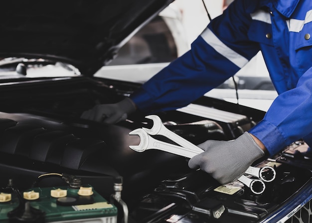 Foto mecânico trabalha no motor do carro na garagem. conceito de serviço de inspeção de automóveis e serviço de reparação de automóveis.