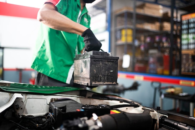 Mecânico trocando bateria de carro Um engenheiro está substituindo uma bateria de carro porque a bateria do carro está morta conceito cuidado do carro