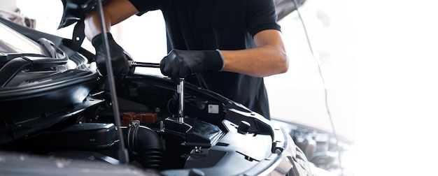 Mecánico usando la llave inglesa para reparar el coche