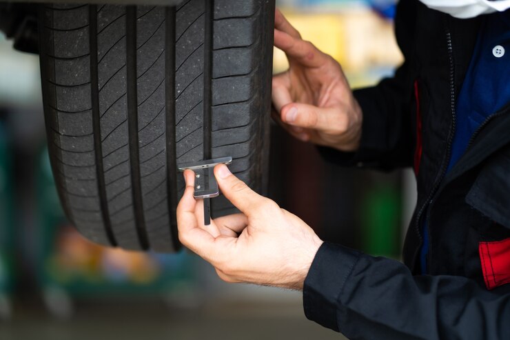 Foto mecânico verificando a profundidade do piso do pneu do carro. manutenção do carro e conceito de garagem de serviço automático.