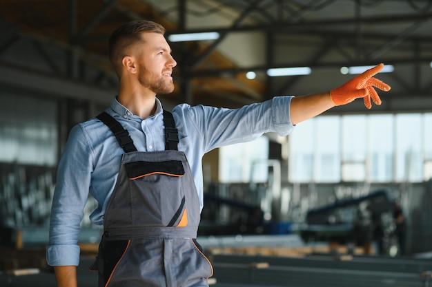 Mecânicos de fábrica masculinos ou engenheiro em uniformes de segurança estão trabalhando em máquinas de perfuração de metal em linhas de produção industrial manutenção mecânica da indústria de processamento de aço