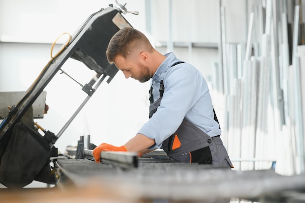 Mecânicos de fábrica masculinos ou engenheiro em uniformes de segurança estão trabalhando em máquinas de perfuração de metal em linhas de produção industrial manutenção mecânica da indústria de processamento de aço