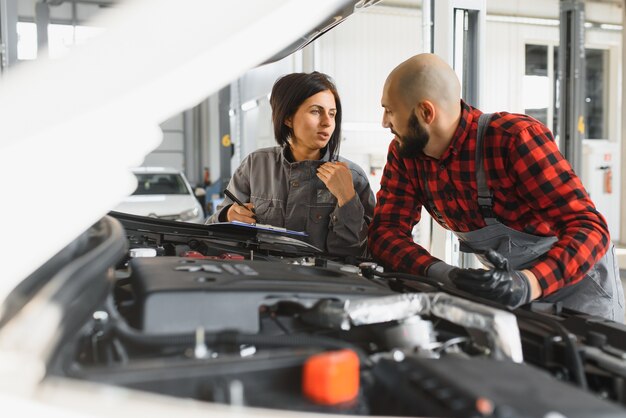 Mecânicos masculinos e femininos trabalhando no carro