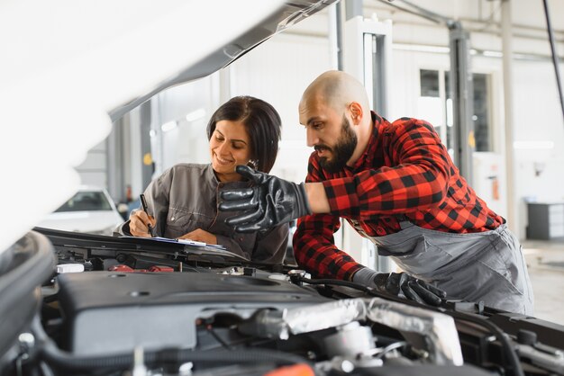 Mecánicos masculinos y femeninos trabajando en coche