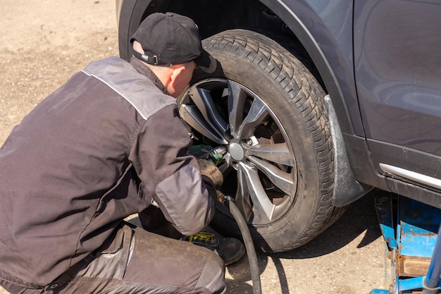 Mechanician mudando a roda de carro na oficina de reparação automóvel