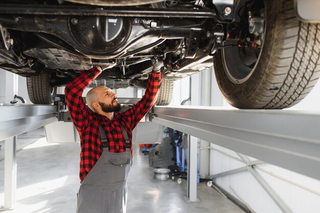 Mechaniker arbeitet unter Auto in der Reparaturwerkstatt