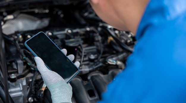 Mechaniker benutzen Smartphone-Reparaturauto