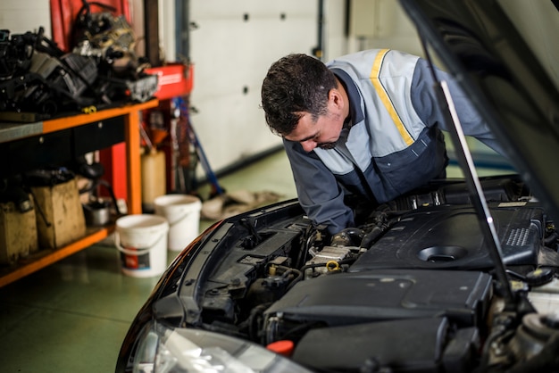 Mechaniker, der an einem Fahrzeug in der Werkstatt arbeitet.