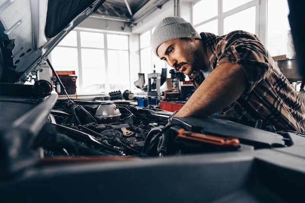 Mechaniker, der auto im autoreparaturservicezentrum untersucht