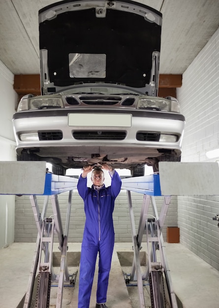 Foto mechaniker, der bei der reparatur eines autos steht