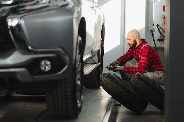 Mechaniker, der einen Autoreifen in einer Werkstatt wechselt