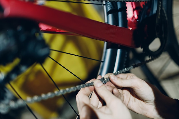 Mechaniker, der kundenspezifisches Fahrrad zusammenbaut und Kettennietglied aus nächster Nähe installiert