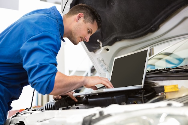 Mechaniker, der Laptop auf Auto verwendet