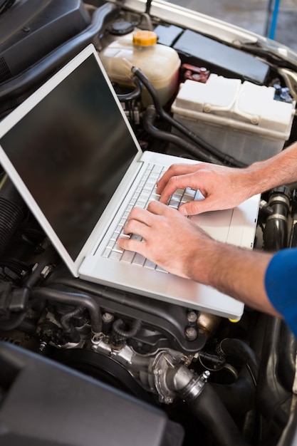 Mechaniker, der Laptop auf Auto verwendet