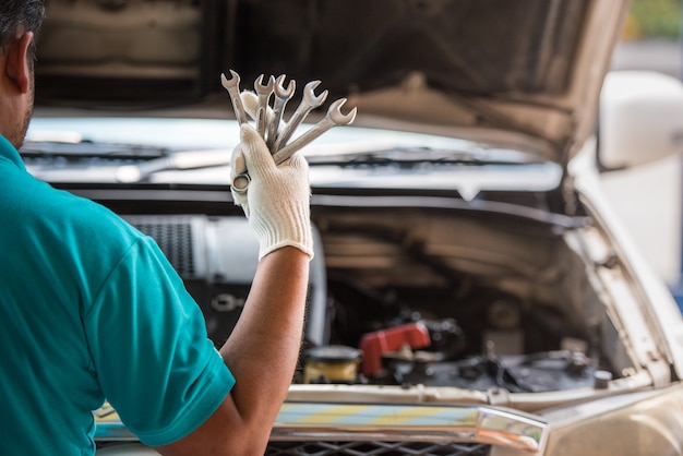 Mechaniker, der Schlüssel in der Hand, Automobilwartungsservice hält.