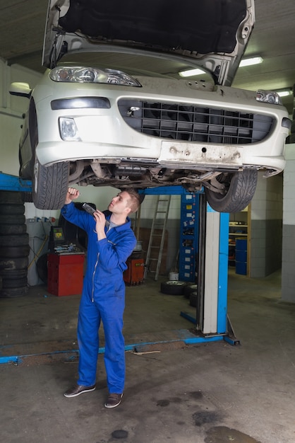 Mechaniker, der unter angehobenem Auto in der Garage arbeitet