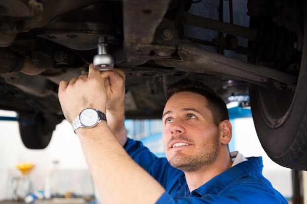 Mechaniker, der unter dem Auto überprüft