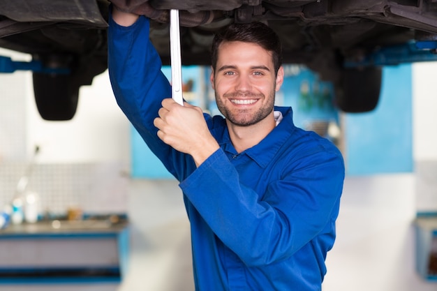 Mechaniker, der unter dem Auto überprüft