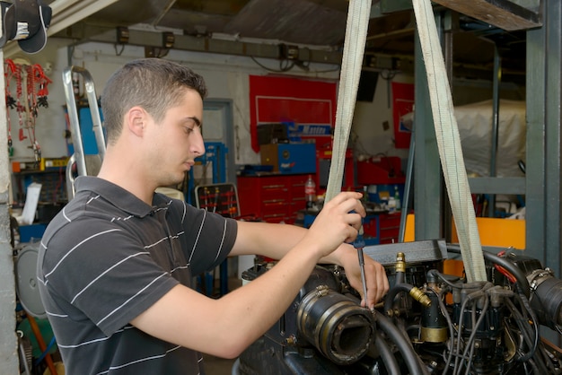 Mechaniker des jungen Mannes, der Motorboote und andere repariert