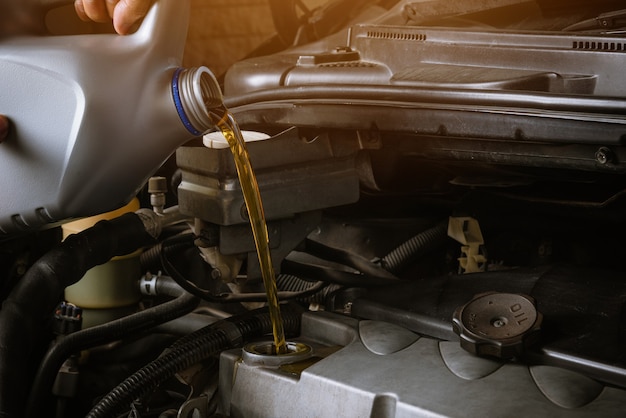 Mechaniker im Einsatz, um das Auto zu reparieren, zu tanken und aus der Flasche zu gießen, um das Schmiermittel zu wechseln