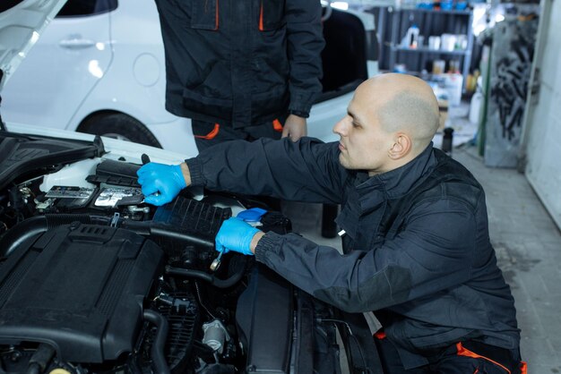 Mechaniker mit Schraubenschlüssel, die Auto in der Werkstatt reparieren.