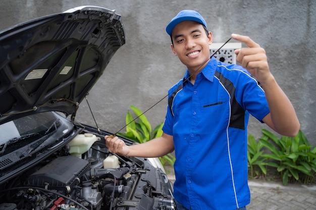 Mechaniker mit Uniform inspiziert das Autoöl