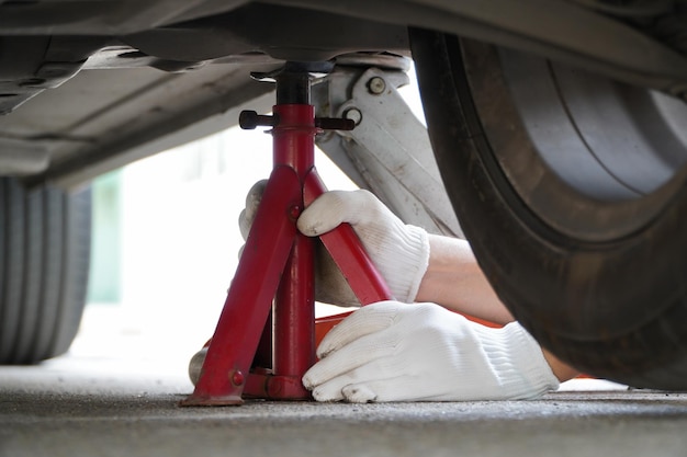 Mechaniker mit weißen Handschuhen benutzt einen Wagenheber, um sicher in Ihrem Auto aufzustehen