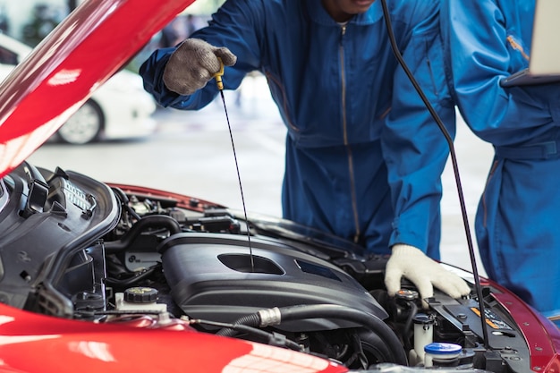 Mechaniker überprüft den Ölstand in der Autogarage, repariert die Autokarriere