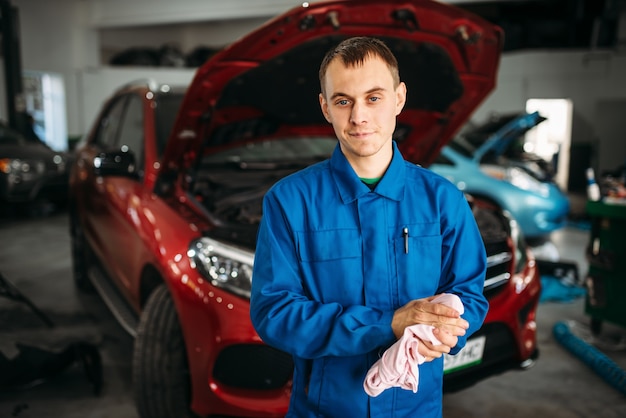 Mechaniker wischt sich die Hände nach der Reparatur des Autos, Motordiagnose.