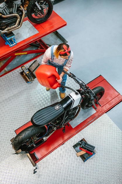Mechanikerin mit Gerry kann den Kraftstofftank des Motorrads in der Fabrik füllen