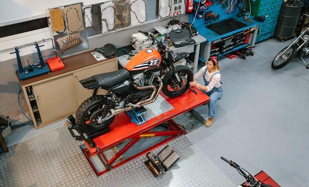 Mechanikerin überprüft ein benutzerdefiniertes Motorrad über der Plattform