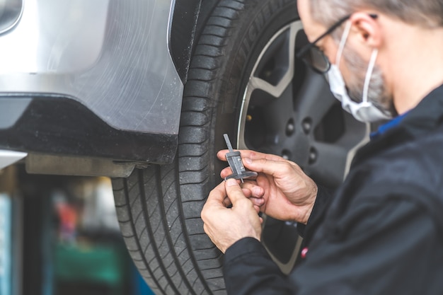 Mechanikerprüfung Überprüfung der Tiefe des Autoreifenprofils. Autowartungs- und Autowerkstattkonzept.