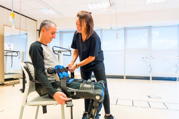 Mechanisches Exoskelett Physiotherapie-Assistent, der einer behinderten Person mit einem Roboterskelett Bänder anlegt Futuristische Rehabilitation Physiotherapie in einem modernen Krankenhaus