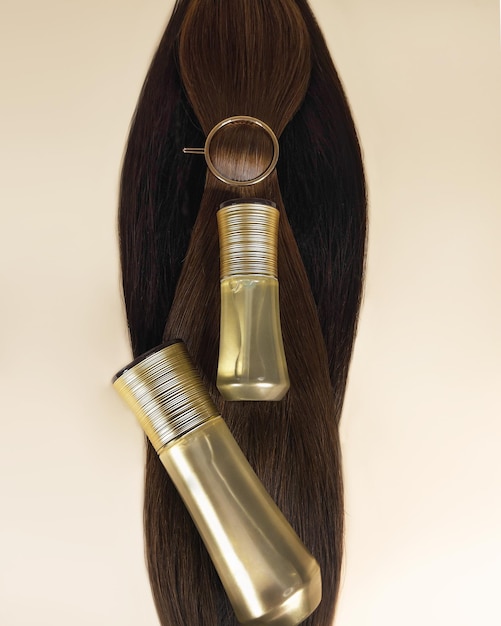 Un mechón de cabello oscuro natural para extensiones con una botella de producto para el cuidado