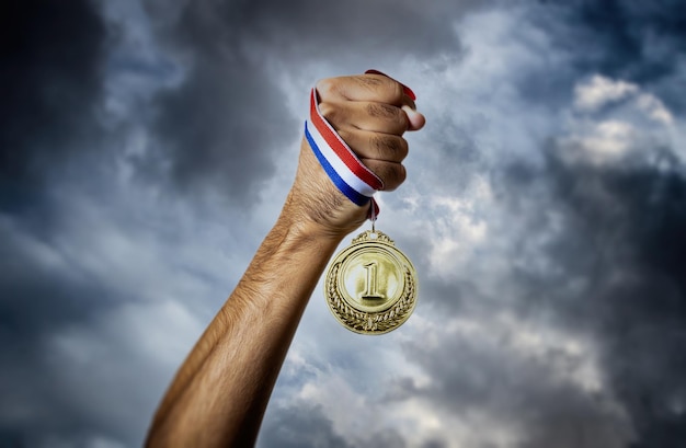 Medaille Gold in der Hand des Gewinners Himmelshintergrund für den ersten Platz Sportmeister Athlet Siegkonzept