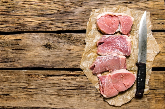 Medaillons aus frischem rohem Fleisch und dem Tranchiermesser. Auf Holztisch. Freier Platz für Text. Draufsicht