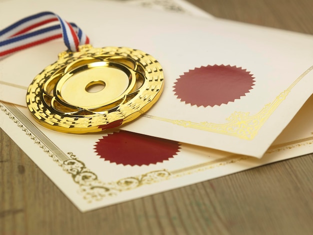 Medalha de ouro e certificados na mesa de madeira