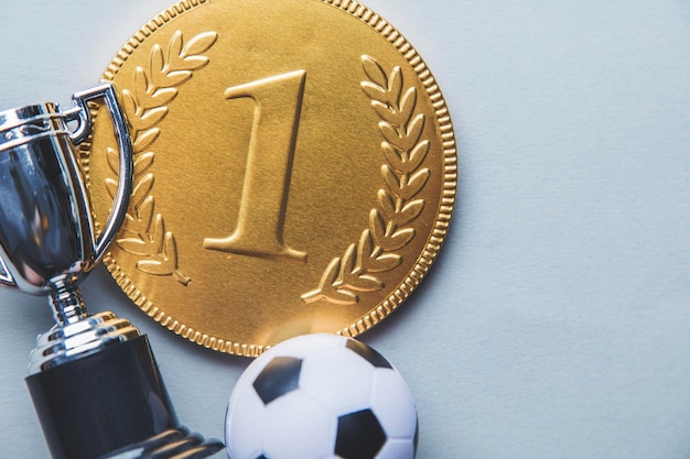 Medalha e troféu dos vencedores do primeiro lugar de ouro com uma bola de futebol Conceito de conquista de sucesso de futebol