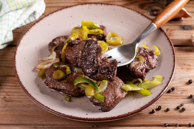 Medalhão de filé de carne suculenta grossa assada rara coberto com alho-poró na mesa de madeira