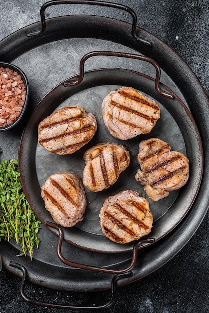 Medalhões de carne de porco assada bifes carne de filé fundo preto vista superior