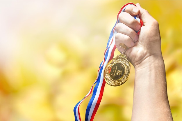 Foto medalla de oro con cinta en mano sobre fondo