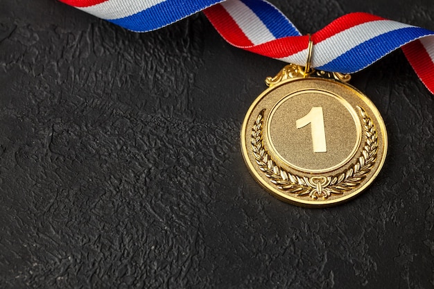 Foto medalla de oro con cintas. premio al primer lugar del concurso. premio al campeón. fondo negro.