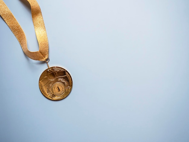 Foto medalla de oro sobre fondo azul.