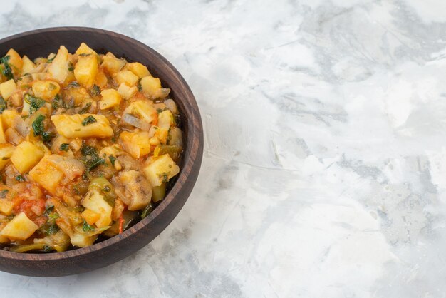 Media foto de una deliciosa cena con patatas verduras verdes en un recipiente marrón en el lado derecho sobre fondo de hielo con espacio libre