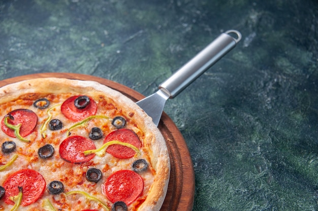 Media foto de deliciosa pizza casera sobre tabla de madera en el lado derecho sobre una superficie oscura